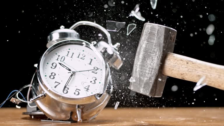 Slow motion medium locked down shot of a ringing two bell alarm clock being smashed by a hammer. Shot in Slovenia.